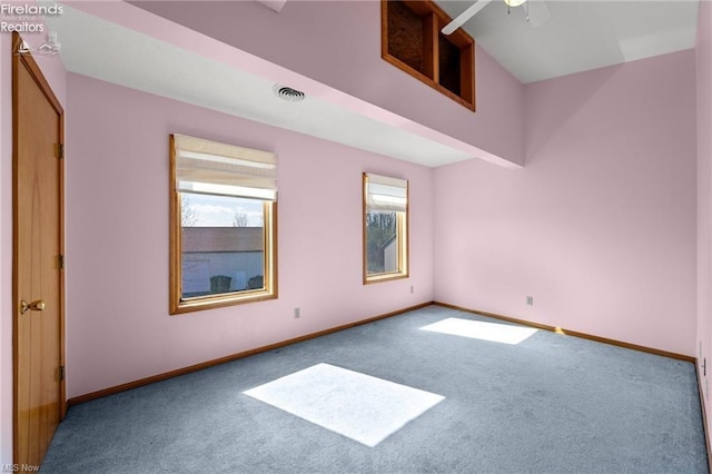 unfurnished room featuring visible vents, baseboards, ceiling fan, carpet floors, and a high ceiling