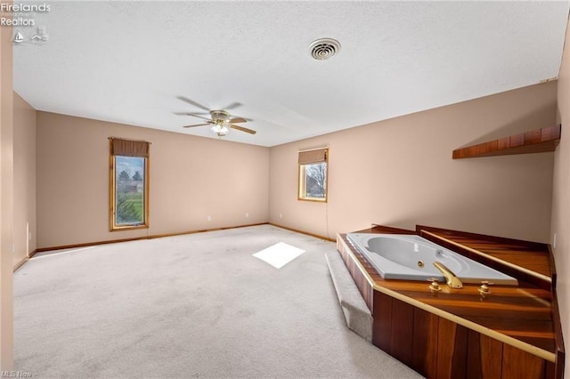 interior space featuring a textured ceiling, baseboards, visible vents, ceiling fan, and carpet
