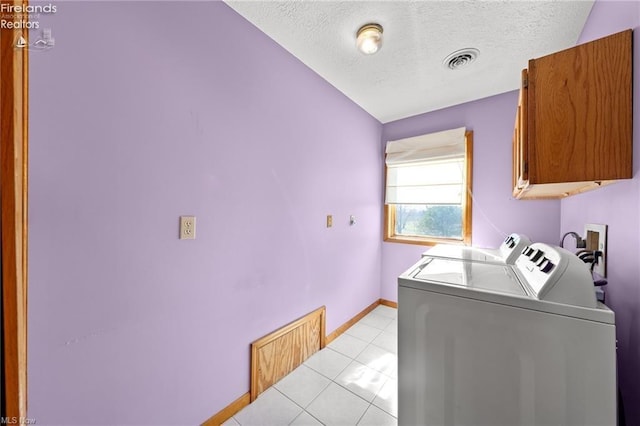 clothes washing area featuring a textured ceiling, light tile patterned flooring, visible vents, cabinet space, and washer and dryer