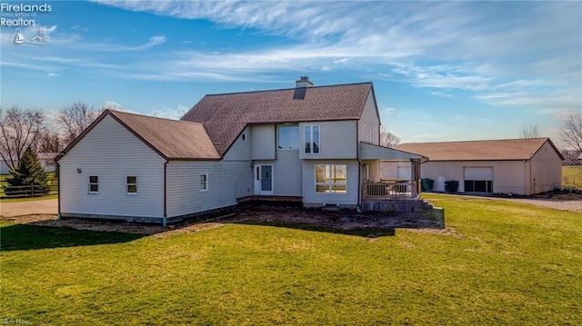 back of property with a chimney, a wooden deck, and a yard