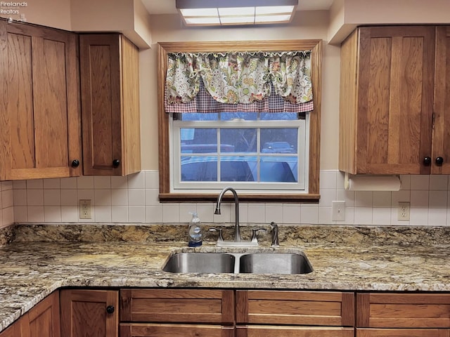 6276 County Road 33, Helena, OH 43435 - kitchen with brown cabinetry, light stone countertops, a sink, and backsplash