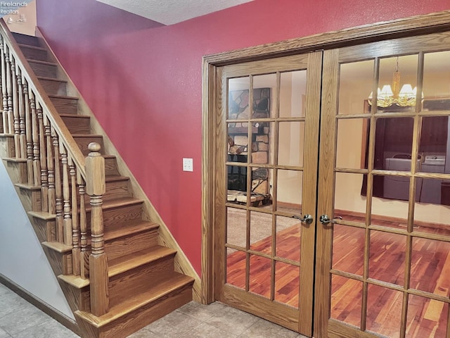 6276 County Road 33, Helena, OH 43435 - staircase with washer / clothes dryer, a notable chandelier, baseboards, french doors, and a textured ceiling