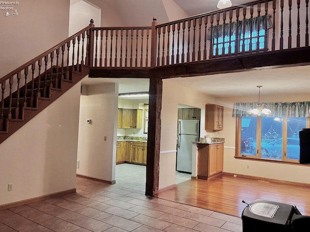 6276 County Road 33, Helena, OH 43435 - unfurnished living room featuring baseboards, a notable chandelier, light wood-style floors, stairway, and a towering ceiling