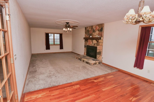 6276 County Road 33, Helena, OH 43435 - unfurnished living room with ceiling fan with notable chandelier, a fireplace, a textured ceiling, wood finished floors, and baseboards