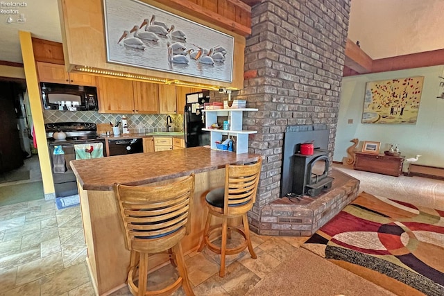 208 Johanna Ln, Kelleys Island, OH 43438 - kitchen with tasteful backsplash, a wood stove, a sink, a peninsula, and black appliances