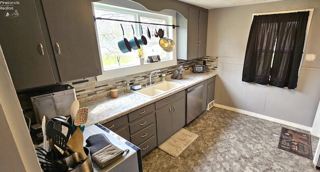 kitchen with dishwasher, a sink, light countertops, gray cabinetry, and a wainscoted wall