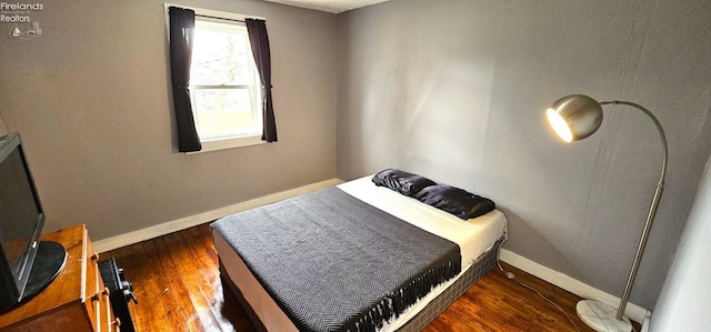 bedroom featuring baseboards and wood finished floors