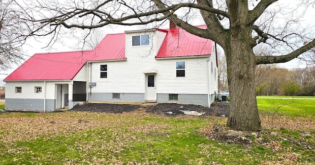 rear view of property featuring metal roof and a lawn