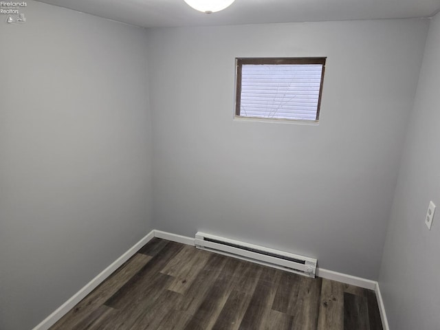 spare room featuring baseboard heating, dark wood-style flooring, and baseboards