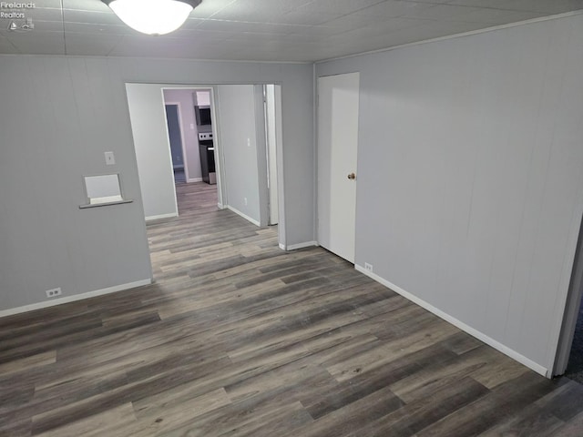 spare room featuring dark wood-type flooring and baseboards