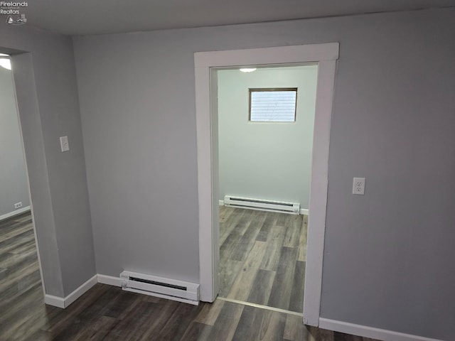 corridor featuring a baseboard radiator, baseboards, and wood finished floors