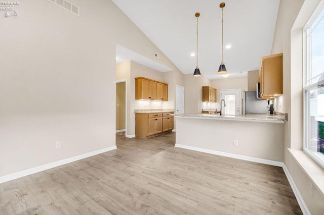 kitchen with high vaulted ceiling, a peninsula, a healthy amount of sunlight, and light wood-style flooring