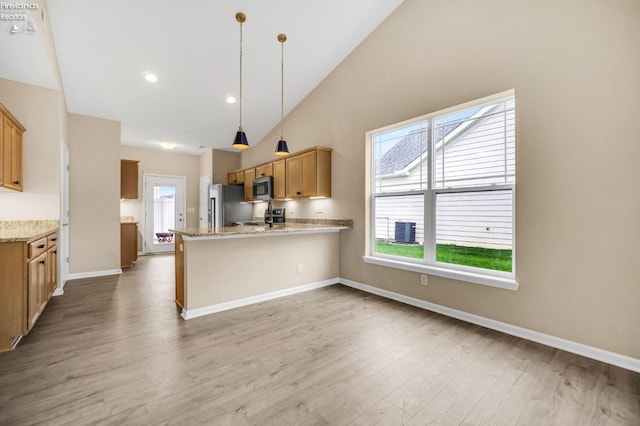 kitchen with a peninsula, stainless steel appliances, light wood finished floors, and a wealth of natural light