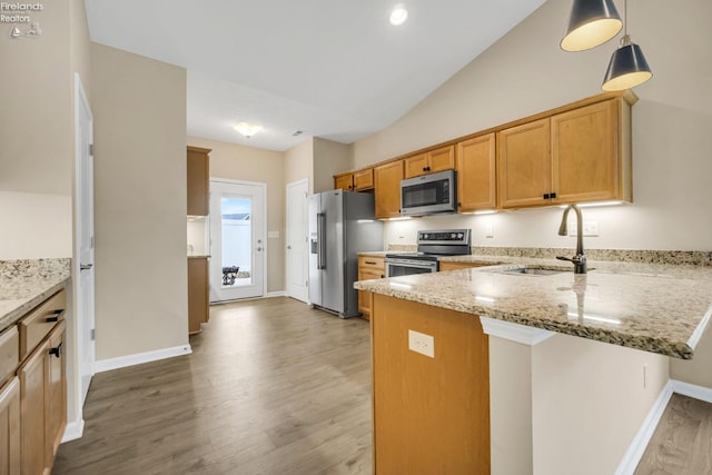 kitchen featuring a sink, light wood-style floors, a peninsula, appliances with stainless steel finishes, and light stone countertops