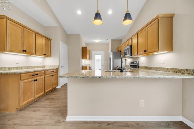 kitchen featuring a peninsula, light wood-style flooring, stainless steel appliances, a sink, and light stone counters