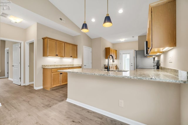 kitchen with a sink, light wood-style flooring, a peninsula, light stone countertops, and visible vents