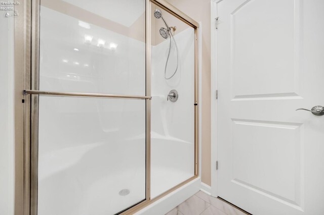 full bathroom with marble finish floor and a stall shower