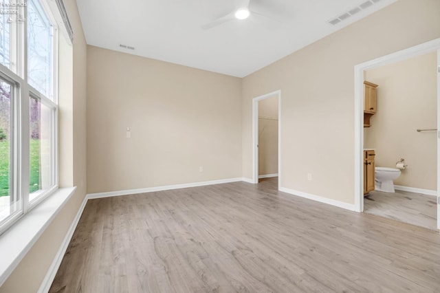spare room featuring visible vents, light wood finished floors, baseboards, and ceiling fan