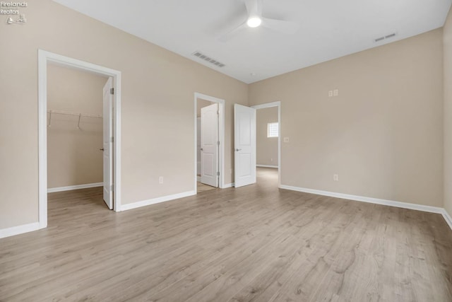 unfurnished bedroom with a walk in closet, light wood-type flooring, and visible vents