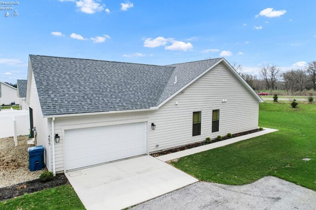 view of front facade with fence, a shingled roof, a front lawn, concrete driveway, and an attached garage