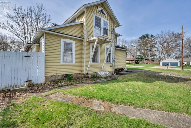 view of side of home with fence and a lawn