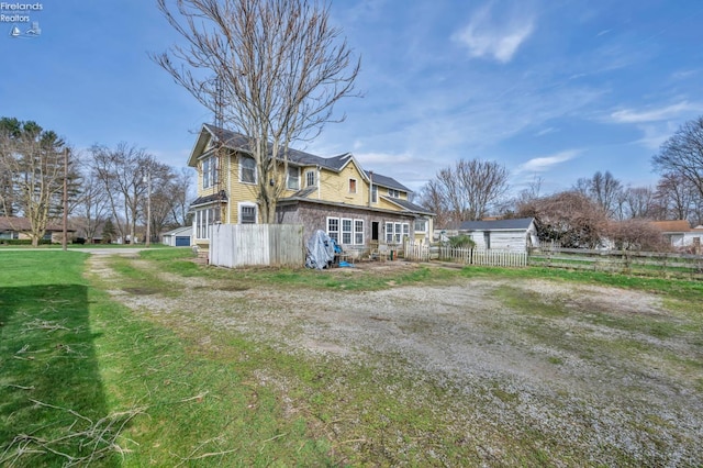 rear view of property featuring a yard and fence
