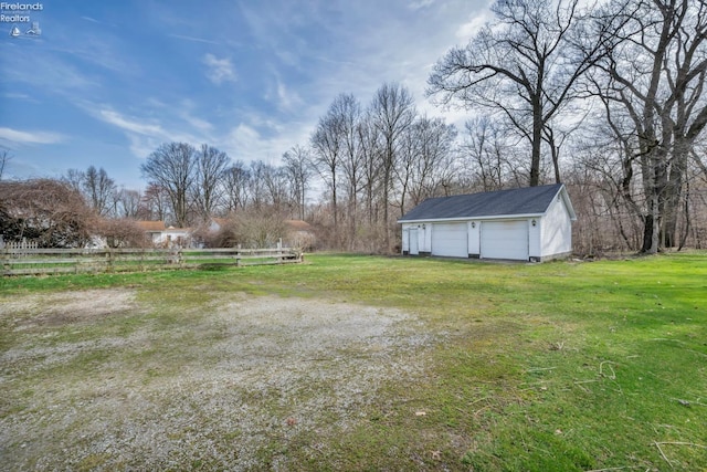 view of yard with a detached garage, fence, and an outdoor structure