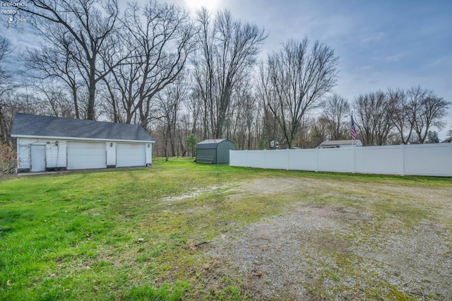view of yard featuring a garage, an outdoor structure, and fence