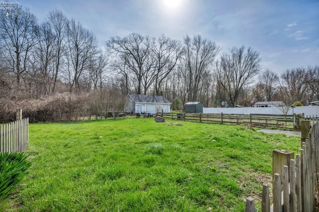 view of yard featuring a rural view, fence, and an outbuilding