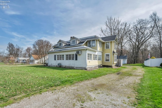 view of side of home featuring a wall mounted AC, a yard, an outdoor structure, and dirt driveway