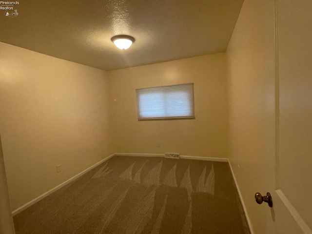 carpeted empty room with a textured ceiling, baseboards, and visible vents