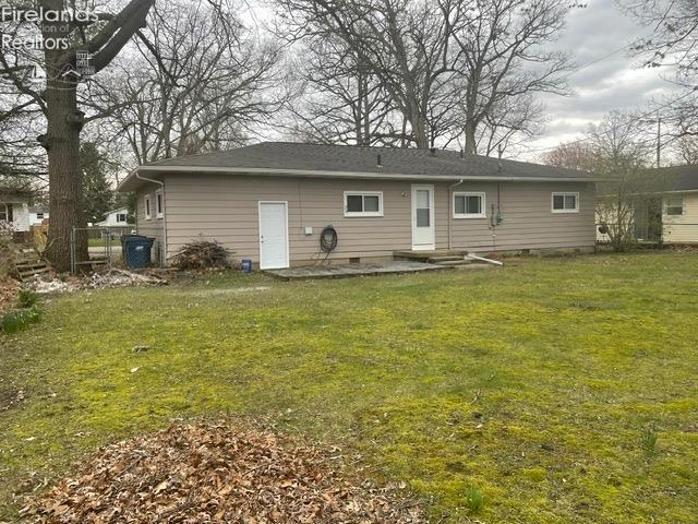 rear view of house with crawl space, fence, and a lawn