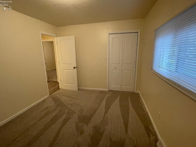 unfurnished bedroom featuring a closet, baseboards, and carpet