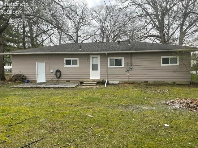back of house with crawl space, a lawn, a patio, entry steps, and roof with shingles