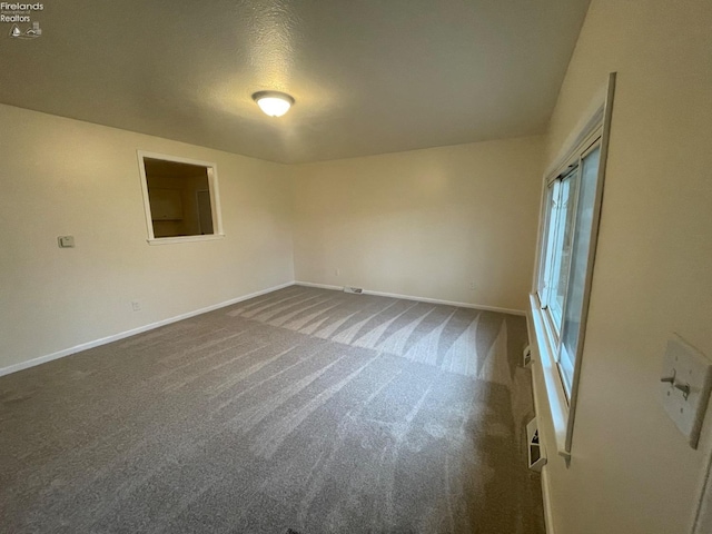 carpeted spare room featuring baseboards