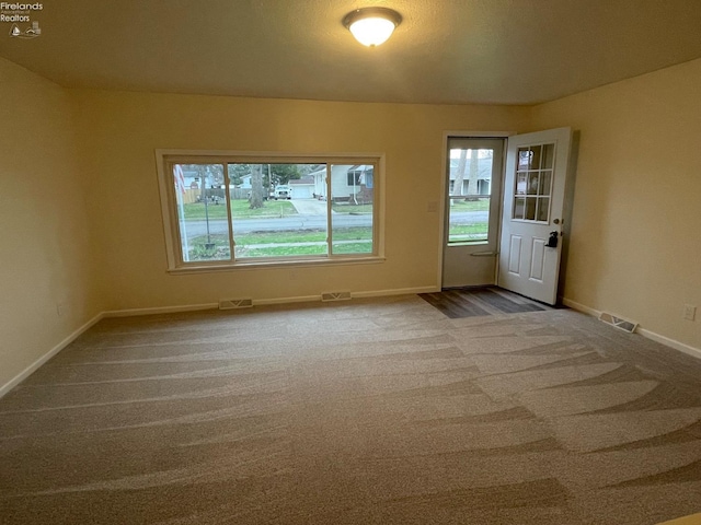 empty room featuring visible vents, baseboards, and carpet