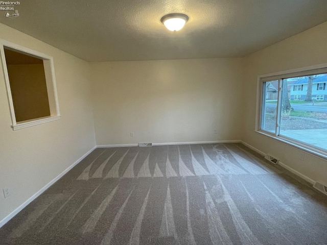 unfurnished room featuring carpet flooring, visible vents, and baseboards