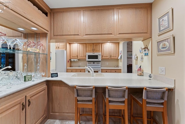 526 Mariner Vlg, Huron, OH 44839 - kitchen featuring a sink, a breakfast bar, white appliances, a peninsula, and light stone counters