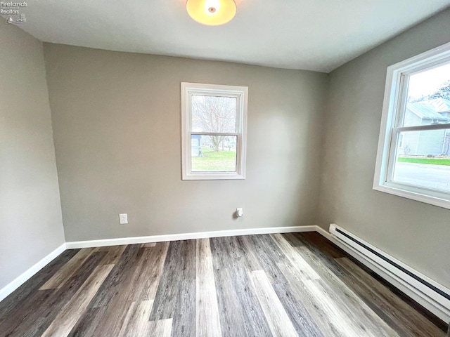empty room with baseboards, dark wood-style floors, and baseboard heating