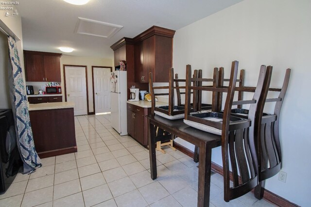 3510 Ohio St, Sandusky, OH 44870 - kitchen with freestanding refrigerator, light tile patterned floors, dark brown cabinets, light countertops, and baseboards