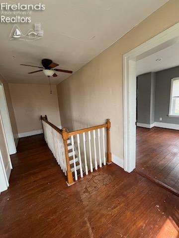 staircase with hardwood / wood-style floors, baseboards, and a ceiling fan