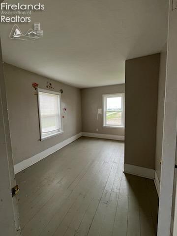 unfurnished room featuring wood-type flooring and baseboards