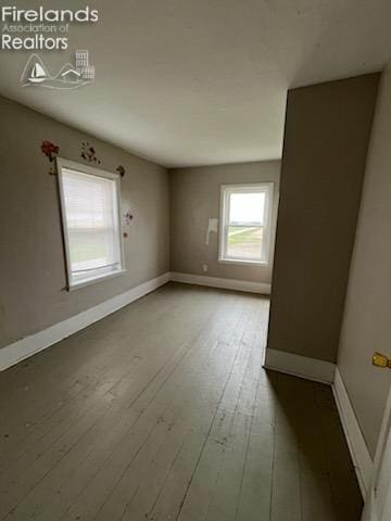 spare room with wood-type flooring and baseboards