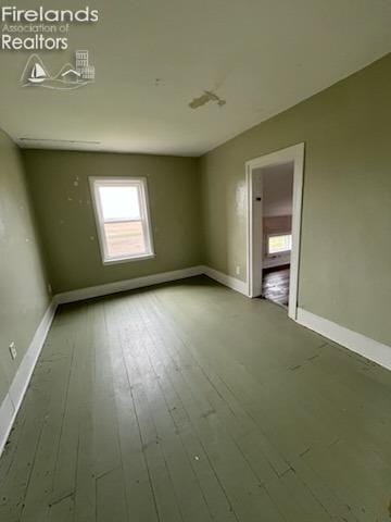 unfurnished room featuring wood-type flooring and baseboards