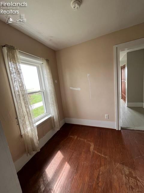 spare room featuring hardwood / wood-style flooring and baseboards