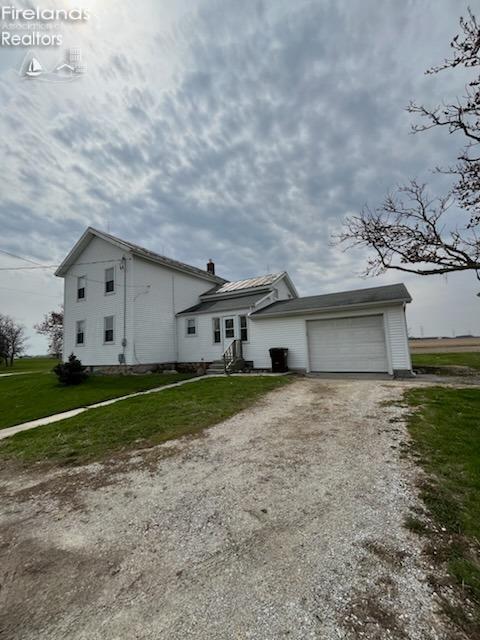 view of front facade featuring a front yard, dirt driveway, entry steps, and a garage