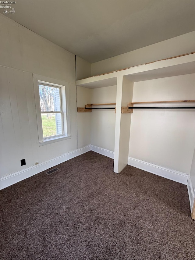 unfurnished bedroom with visible vents, baseboards, and dark colored carpet