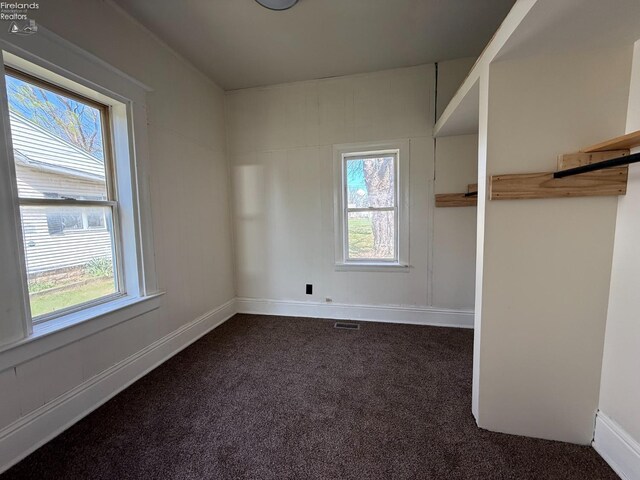 spare room featuring dark carpet, baseboards, and visible vents