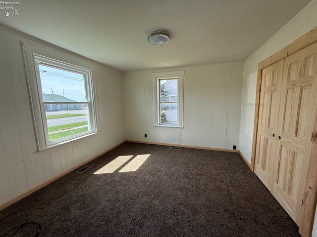 unfurnished bedroom featuring visible vents, baseboards, multiple windows, and carpet