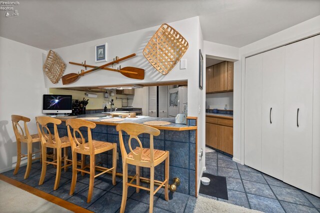 kitchen featuring white fridge and brown cabinets